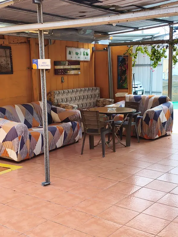 Sala de estar techada con sillones y mesa de comedor